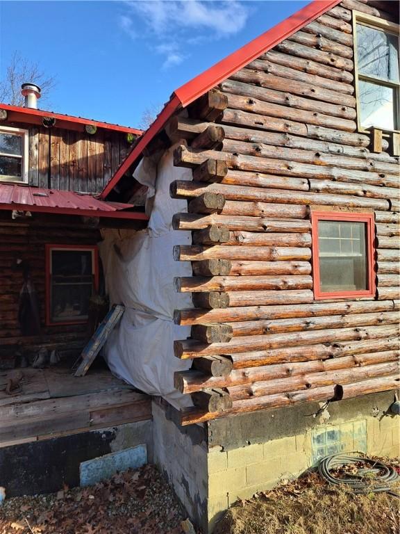 view of side of property with crawl space, log exterior, and metal roof