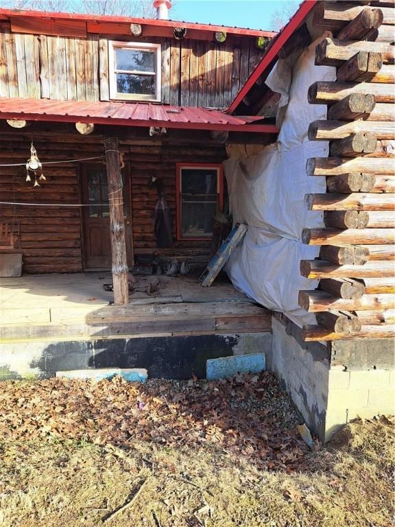 view of exterior entry with metal roof and log exterior