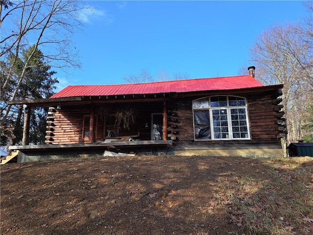 back of house featuring log siding and metal roof