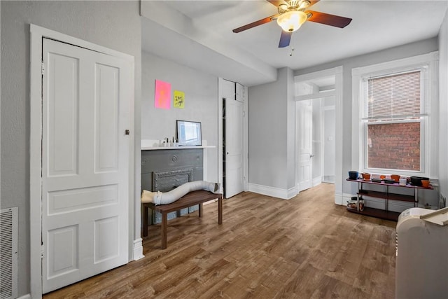 interior space with visible vents, ceiling fan, baseboards, and wood finished floors