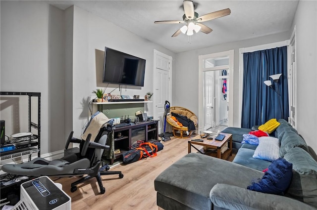 living room with baseboards, wood finished floors, and a ceiling fan