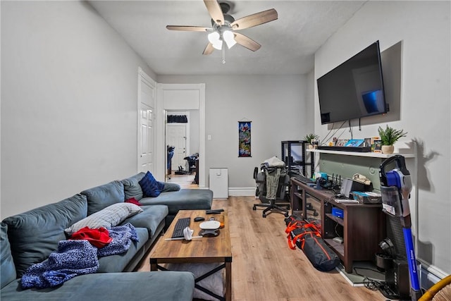 living room featuring ceiling fan, baseboards, and wood finished floors