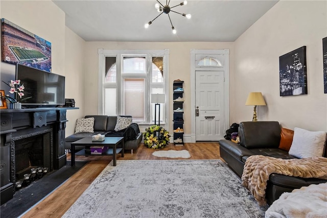 living room featuring an inviting chandelier, wood finished floors, and a fireplace