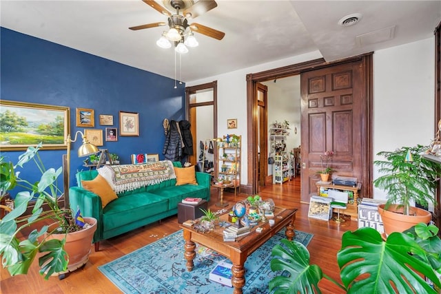 living area with visible vents, a ceiling fan, and wood finished floors