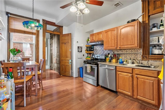 kitchen featuring visible vents, a sink, tasteful backsplash, stainless steel appliances, and light wood finished floors