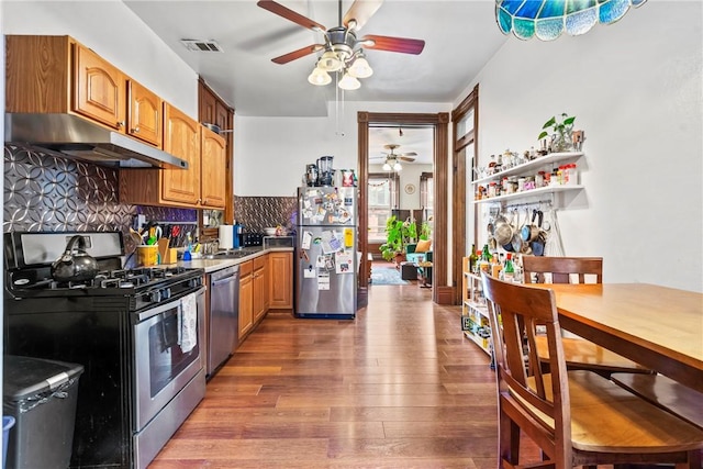 kitchen featuring visible vents, under cabinet range hood, backsplash, stainless steel appliances, and light wood-style floors