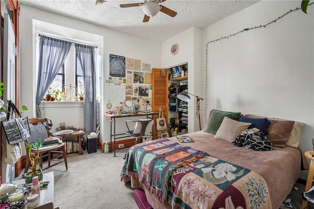 carpeted bedroom featuring ceiling fan and a textured ceiling