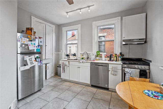 kitchen featuring under cabinet range hood, a sink, white cabinetry, stainless steel appliances, and light countertops