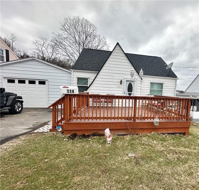 back of house with a yard, a garage, and roof with shingles