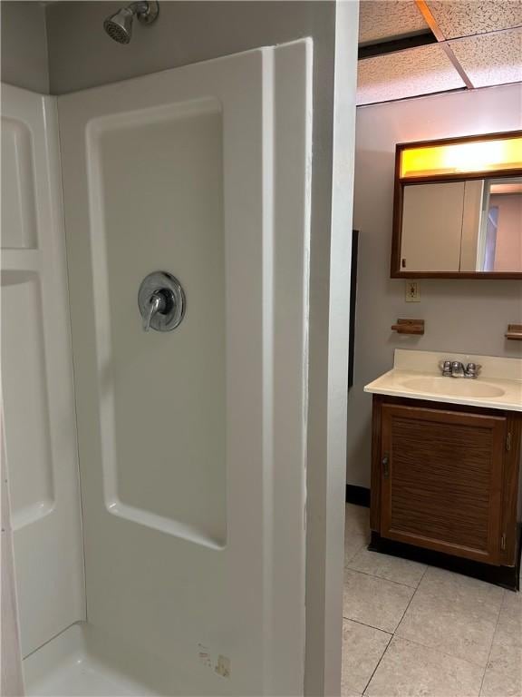 full bath with tile patterned floors, a drop ceiling, vanity, and a shower