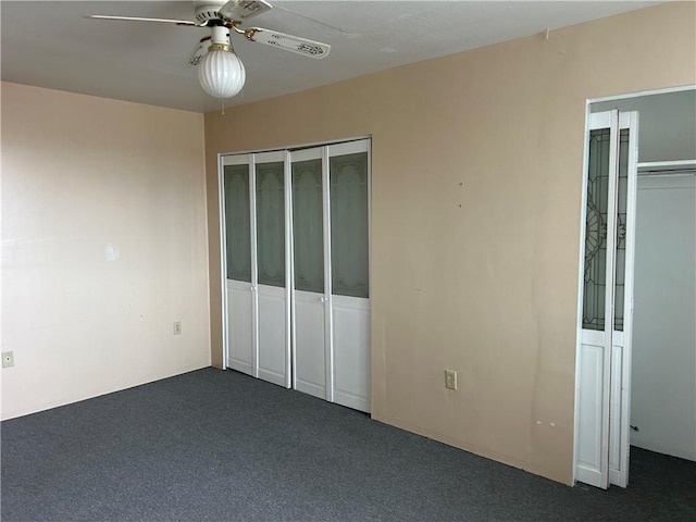 unfurnished bedroom featuring two closets, a ceiling fan, and dark colored carpet