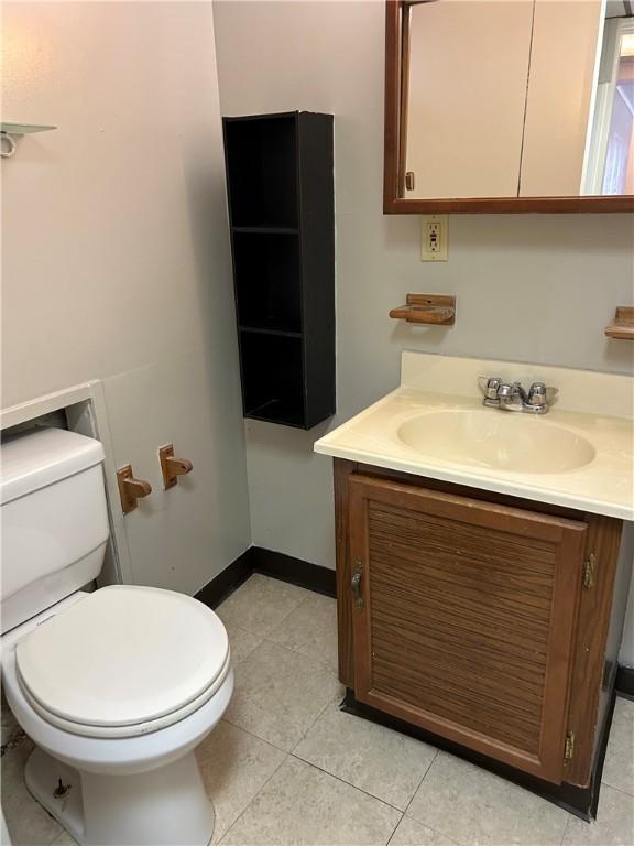 bathroom with tile patterned floors, toilet, vanity, and baseboards