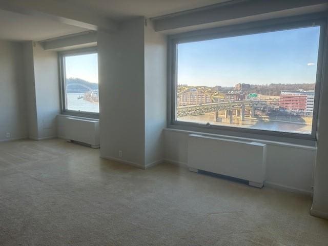 spare room featuring a view of city, radiator, and baseboards