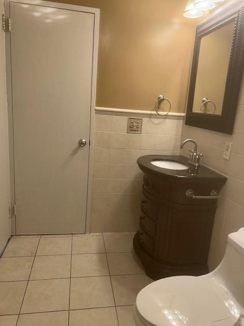 bathroom featuring vanity, tile patterned floors, toilet, and tile walls