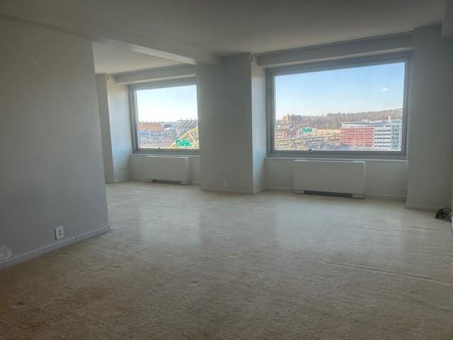 unfurnished room with radiator heating unit and baseboards