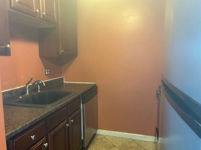 kitchen with baseboards, refrigerator, a sink, dark brown cabinets, and dishwasher