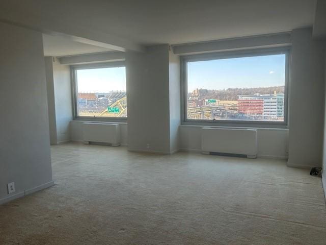 empty room with baseboards, carpet, and radiator heating unit