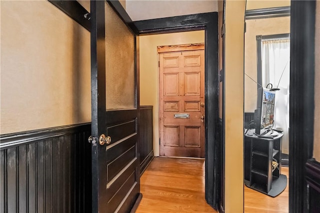 doorway to outside featuring a wainscoted wall and light wood-style flooring