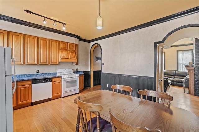 kitchen featuring a wainscoted wall, white appliances, light wood-style floors, and arched walkways