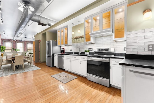 kitchen with light wood-style flooring, a sink, tasteful backsplash, dark countertops, and stainless steel appliances