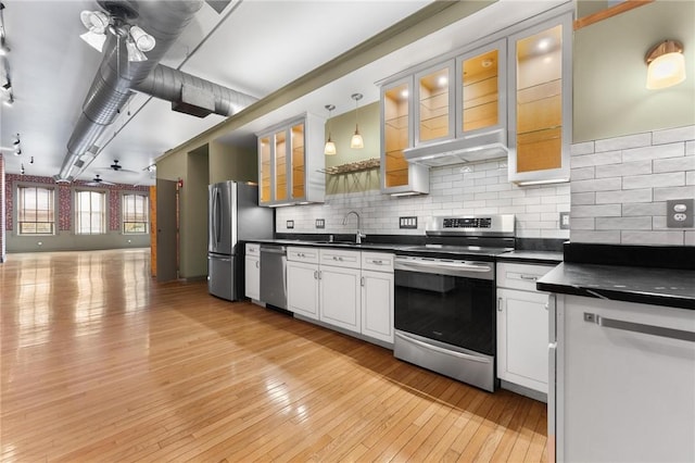 kitchen with dark countertops, light wood-style flooring, backsplash, and stainless steel appliances