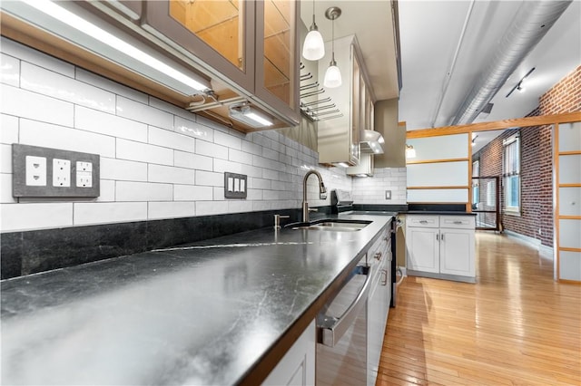 kitchen featuring a sink, dark countertops, appliances with stainless steel finishes, light wood finished floors, and decorative backsplash