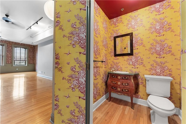 bathroom with wallpapered walls, toilet, baseboards, and wood-type flooring