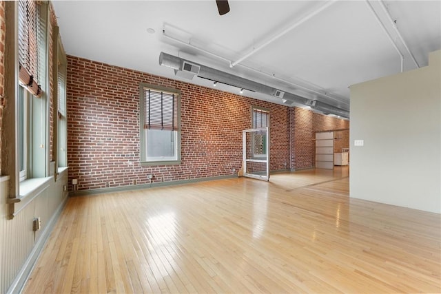 unfurnished room featuring visible vents, brick wall, rail lighting, and hardwood / wood-style flooring