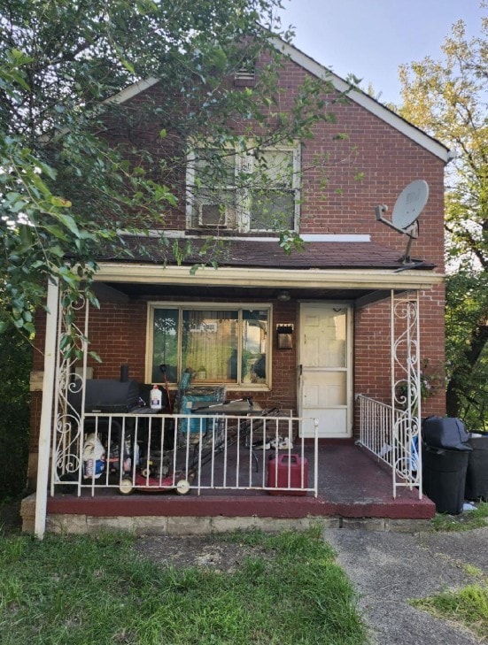 back of property featuring brick siding and covered porch