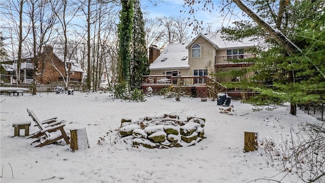 snow covered rear of property with a garage, a chimney, and a deck