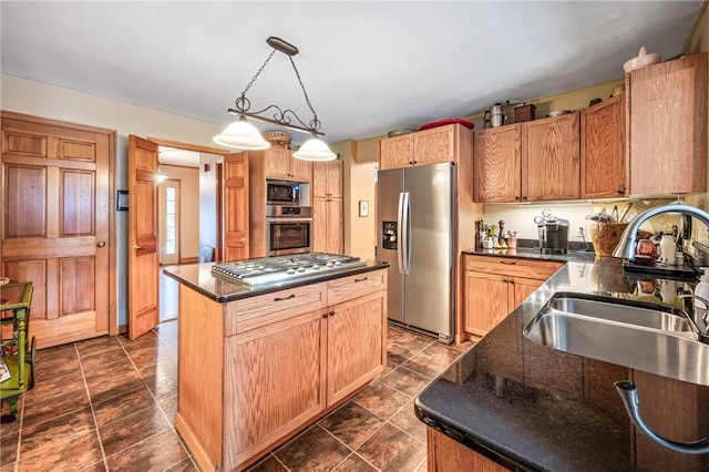 kitchen featuring dark stone counters, a sink, appliances with stainless steel finishes, pendant lighting, and a center island
