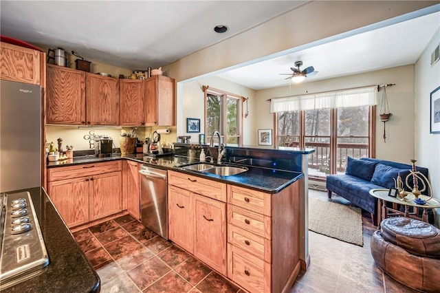 kitchen featuring a ceiling fan, a sink, open floor plan, stainless steel appliances, and a peninsula