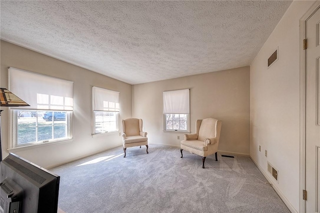 sitting room with a wealth of natural light, visible vents, and carpet