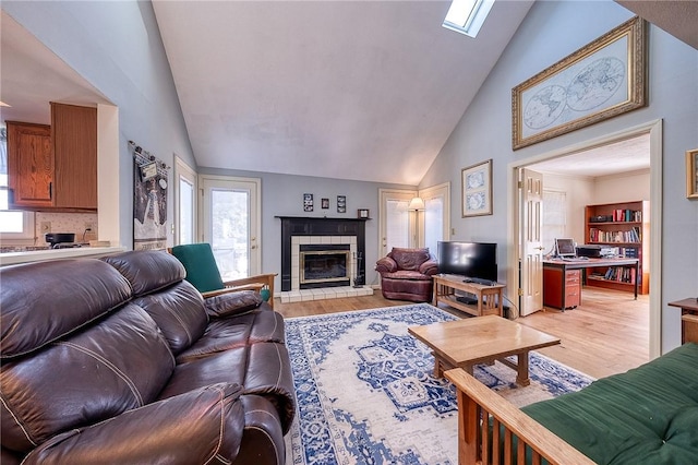 living area with a tiled fireplace, a wealth of natural light, and light wood finished floors