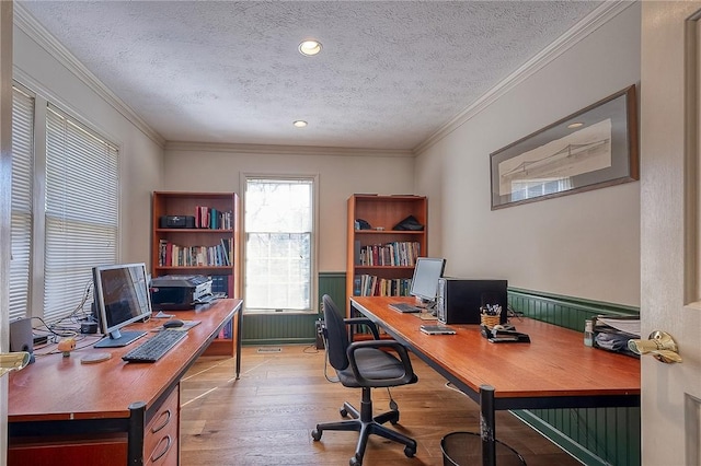 office space with light wood-type flooring, a textured ceiling, wainscoting, and crown molding