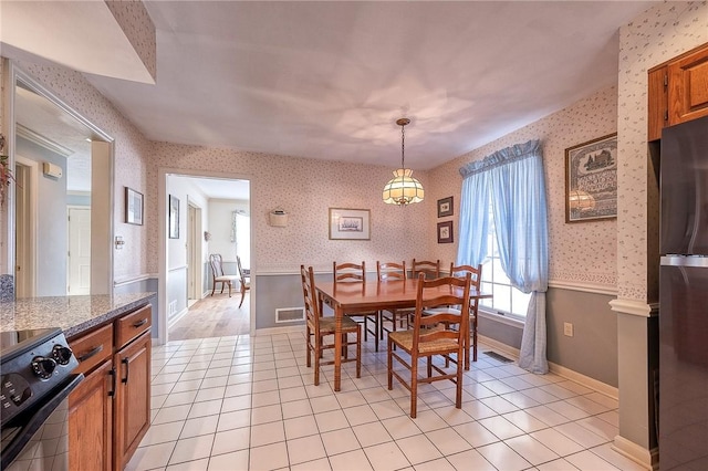 dining area featuring light tile patterned floors, visible vents, wainscoting, and wallpapered walls