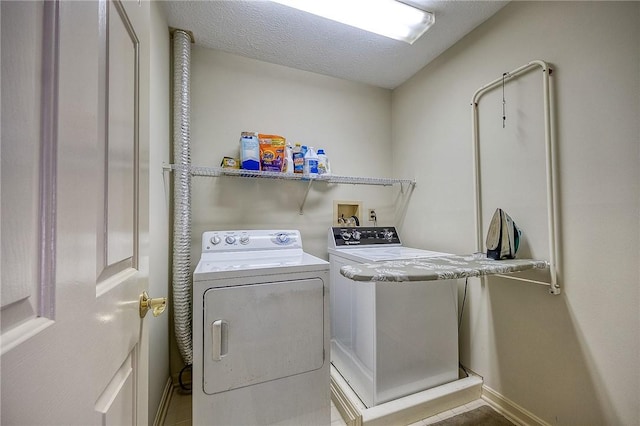 washroom featuring a textured ceiling, laundry area, and washer and clothes dryer