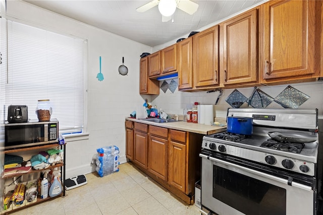 kitchen with brown cabinetry, appliances with stainless steel finishes, light countertops, and a sink