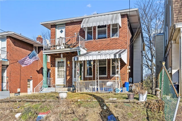 view of front of home with brick siding, a porch, and a balcony