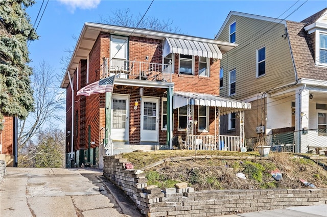 view of front facade featuring brick siding and a balcony