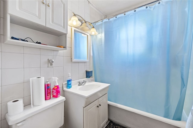 bathroom featuring tasteful backsplash, tile walls, vanity, and toilet