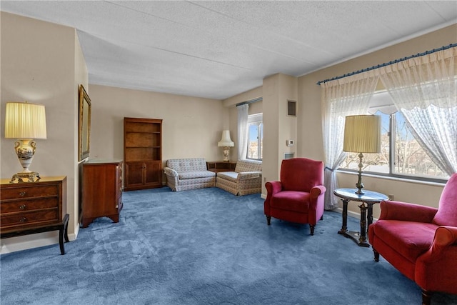 sitting room featuring carpet flooring, baseboards, and a textured ceiling