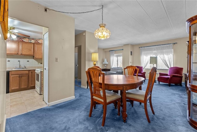 dining room featuring light tile patterned flooring, a ceiling fan, baseboards, and light carpet