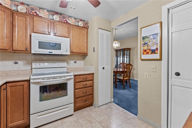 kitchen featuring white appliances, tasteful backsplash, light countertops, and brown cabinets