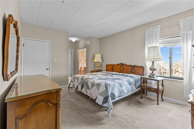 bedroom with light colored carpet, baseboards, and connected bathroom