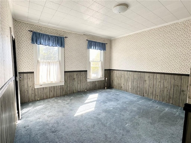 carpeted spare room featuring a wainscoted wall, wallpapered walls, and crown molding