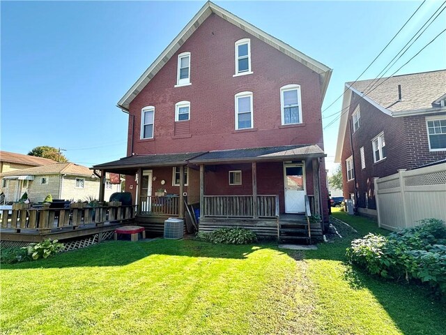 back of property featuring central AC unit, fence, a porch, a yard, and brick siding
