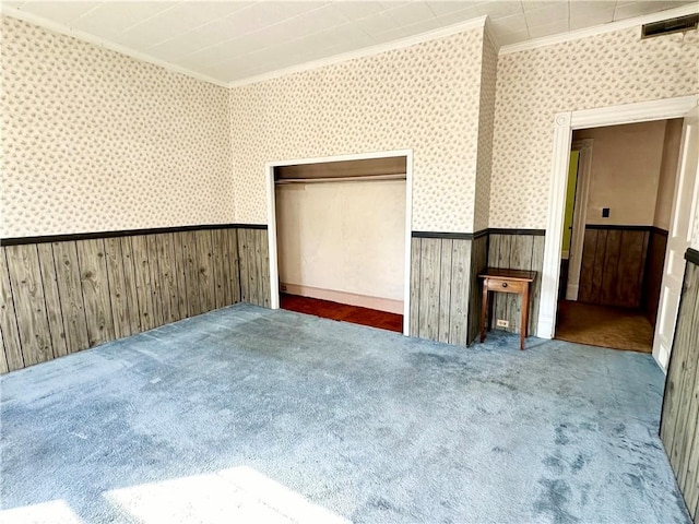 carpeted spare room featuring wallpapered walls, ornamental molding, and wainscoting