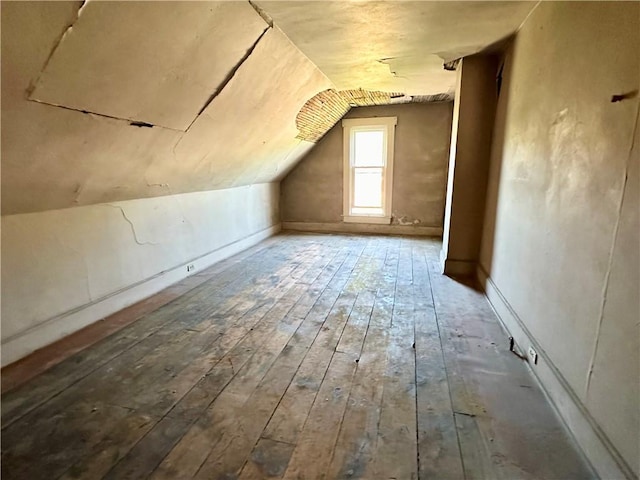 additional living space with hardwood / wood-style floors and vaulted ceiling