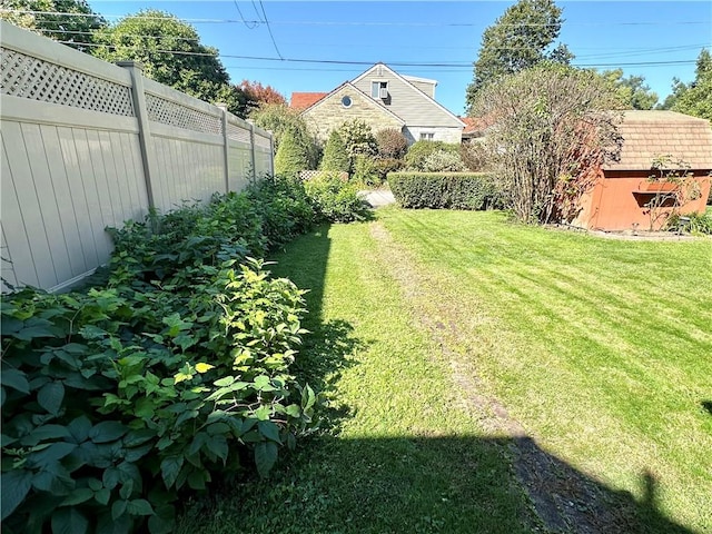 view of yard featuring an outbuilding, a storage unit, and fence